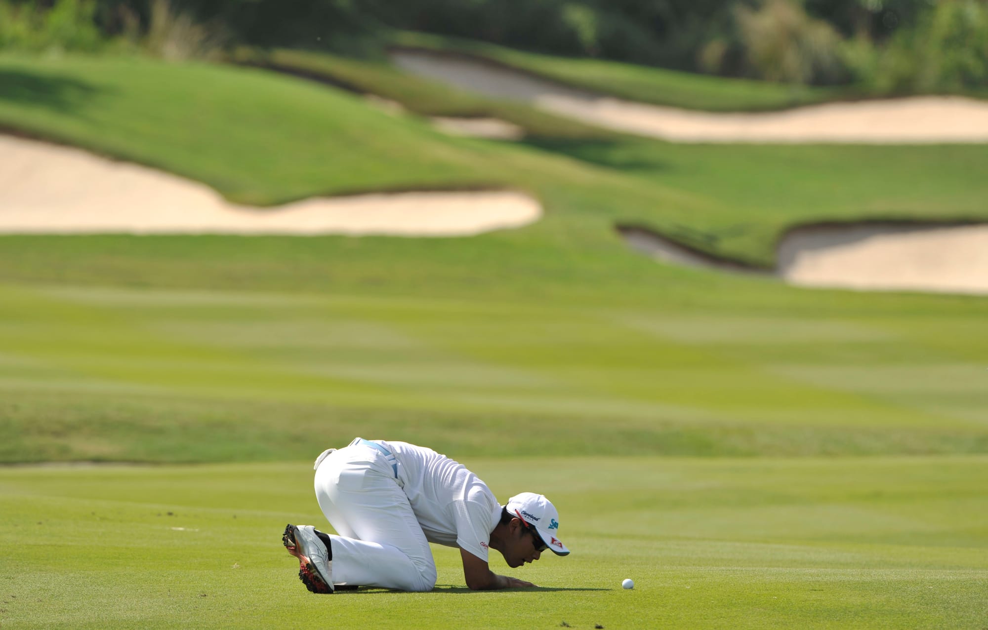 Hideki Matsuyama stoops to identify his ball.