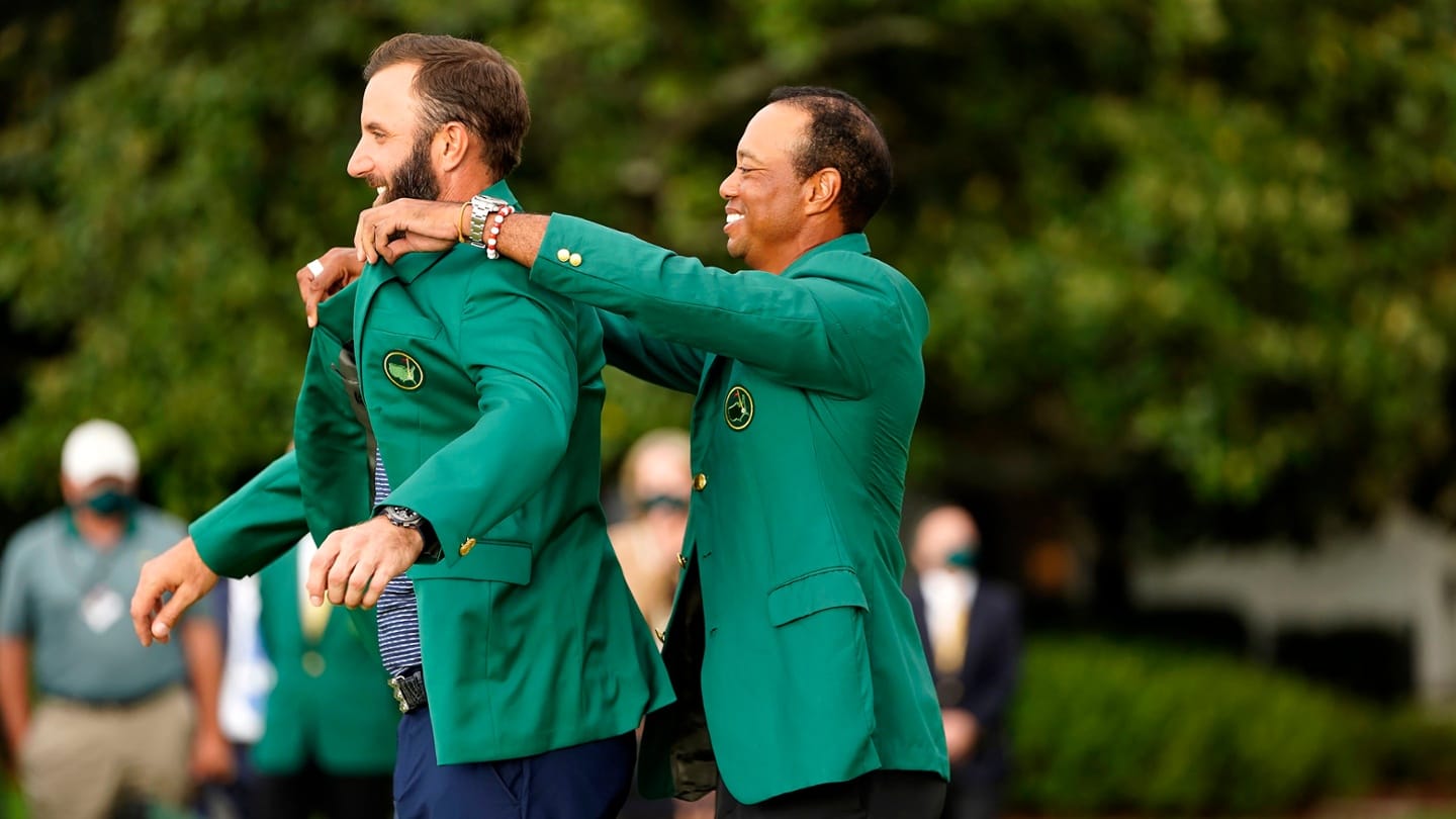 Dustin Johnson is helped into his Green Jacket by 2019 champion Tiger Woods. Picture by Logan Whitton/Augusta National.