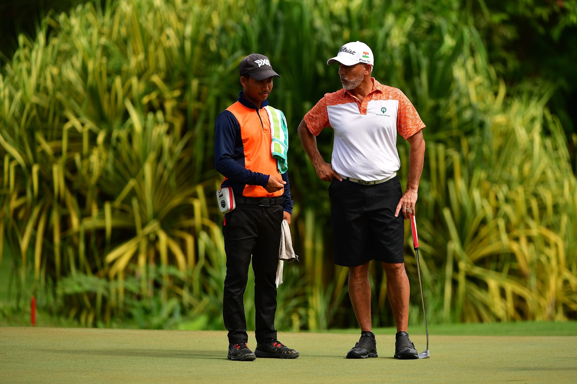 Ex-Asian Games team gold medallist Rishi Narain of India consults with his caddie. 
