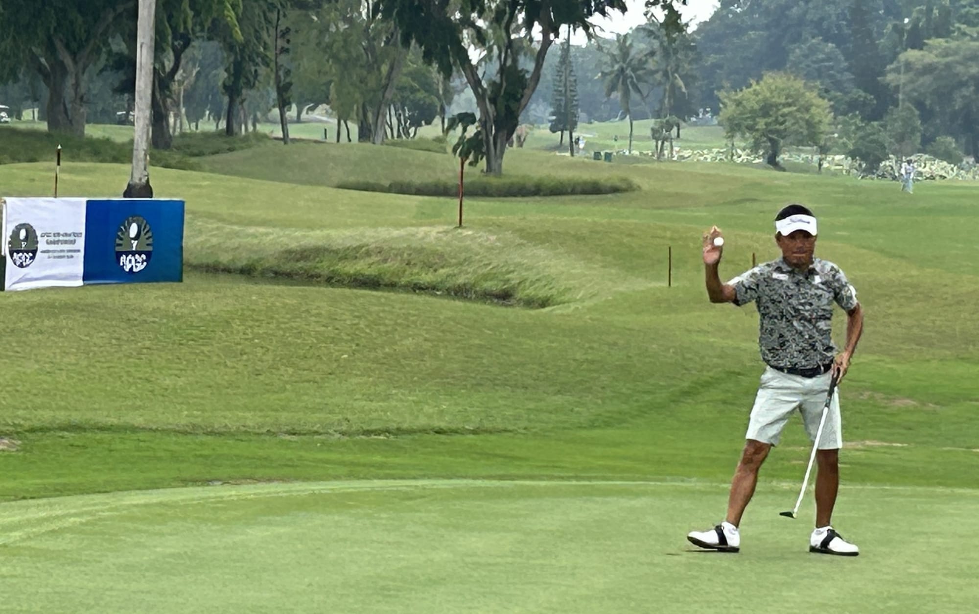 Yutaka Toyoshima acknowledges the applause of the galleries after holing out for a birdie on the final green at Gading Raya.